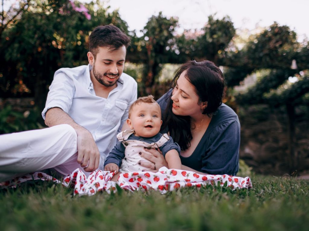 A joyful family bonding with their baby on a picnic in a sunny park