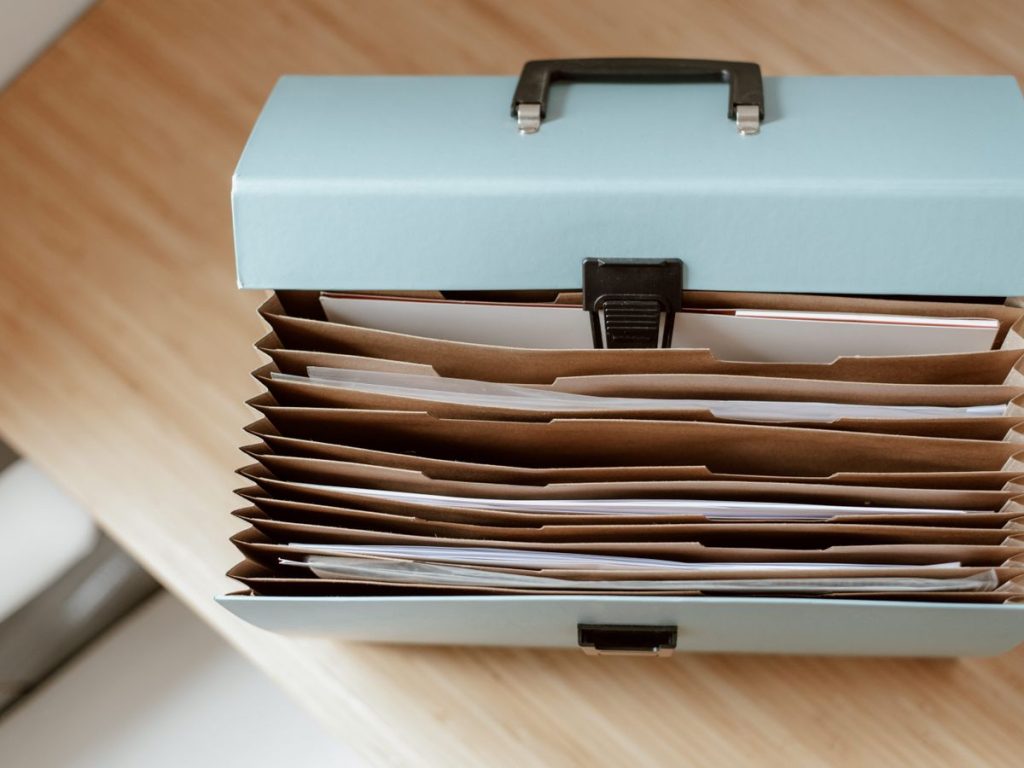 From above of briefcase for documents with papers placed on wooden table in daytime
