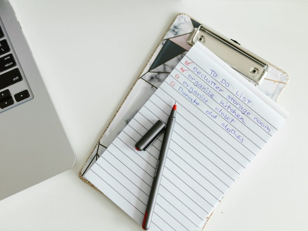 A neatly organized to-do list on a clipboard next to a laptop and pen, conveying productivity
