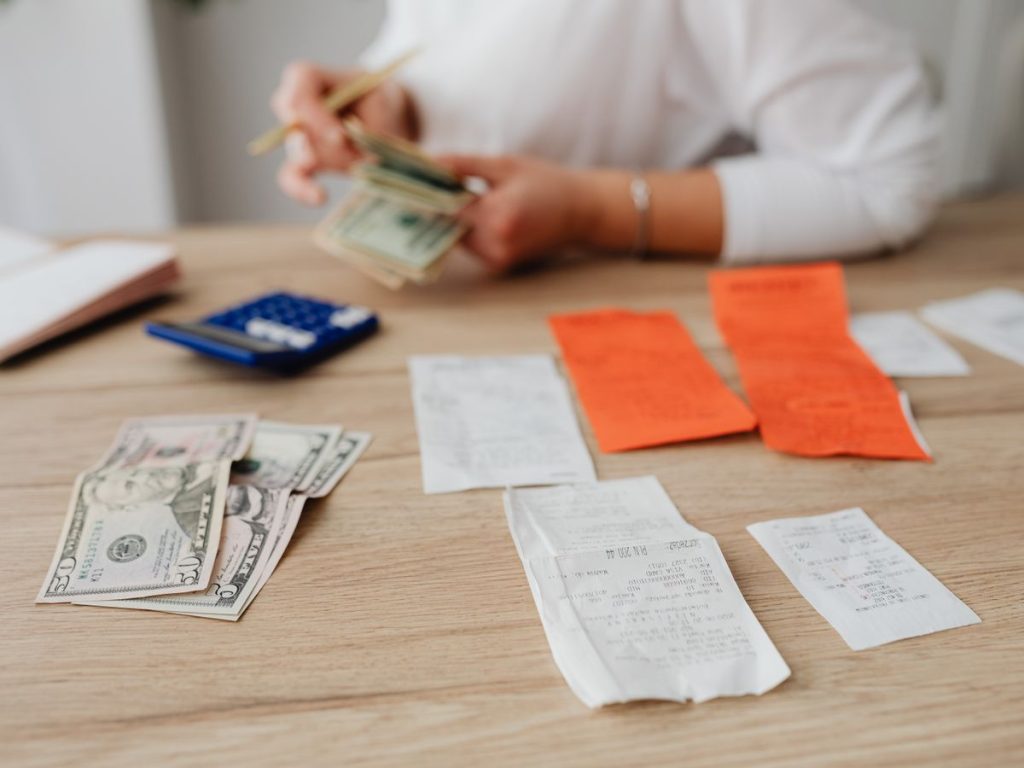 A person using a calculator and cash to plan a household budget