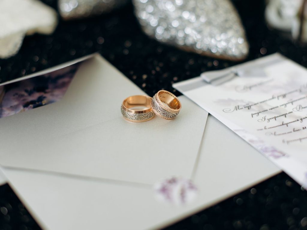 Close-up of elegant wedding rings placed on wedding invitation cards