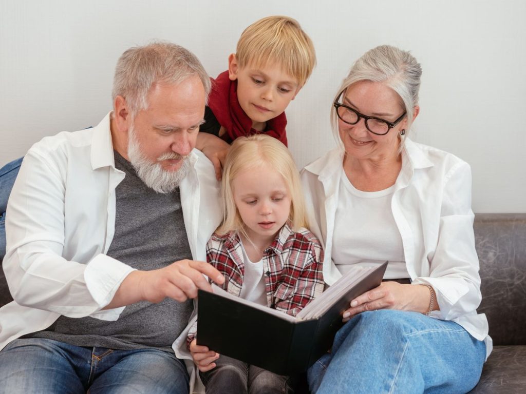 Grandparents and grandchildren reading a photo album on the couch, embracing family bonds and love