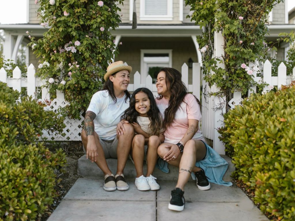 A joyful family of three sitting together outside their home, showing love and happiness