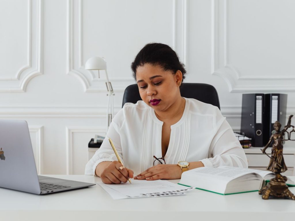 African American woman lawyer signing documents at a desk, symbolizing professionalism