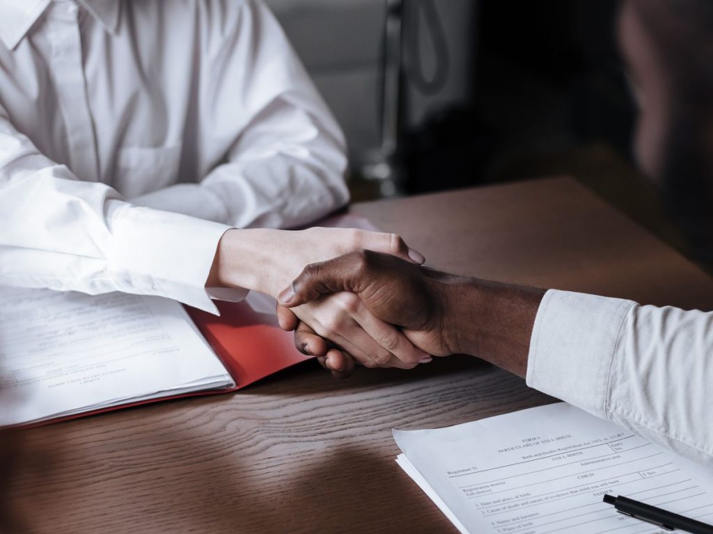 Close-up of a diverse business handshake over documents, symbolizing agreement and collaboration
