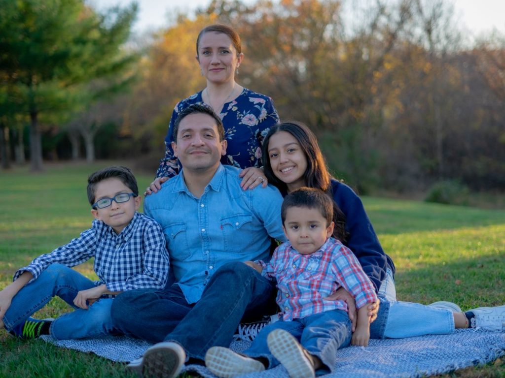 A joyful family sitting together on grass in a park with warm smiles