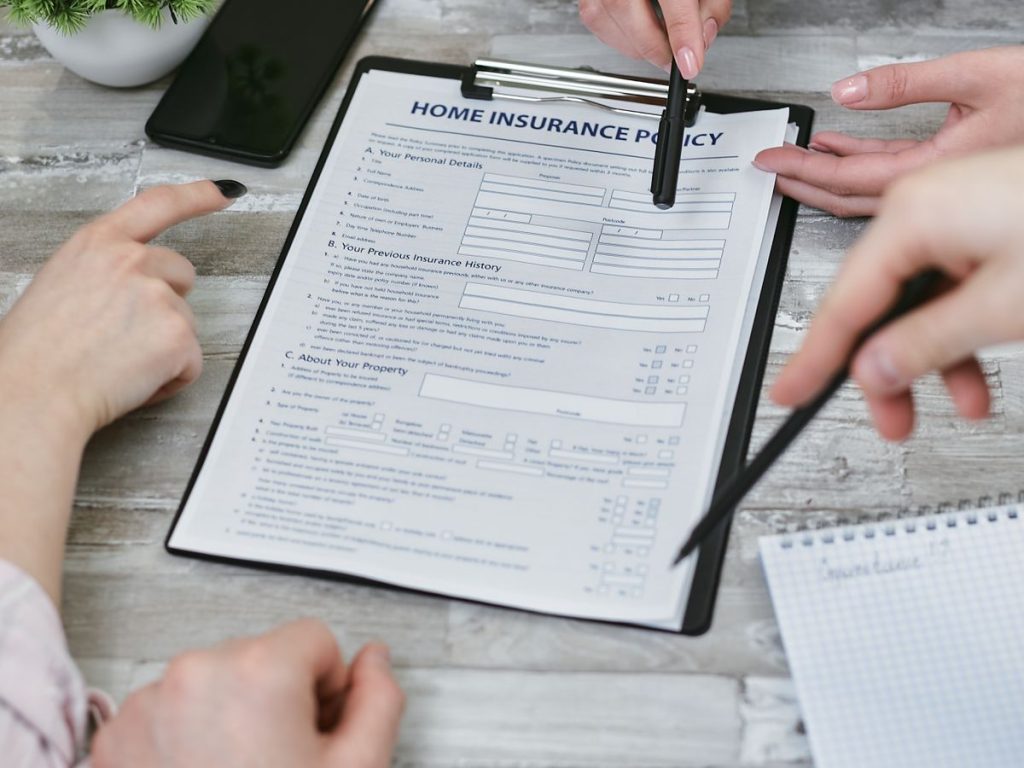 Three people reviewing a home insurance policy on a clipboard