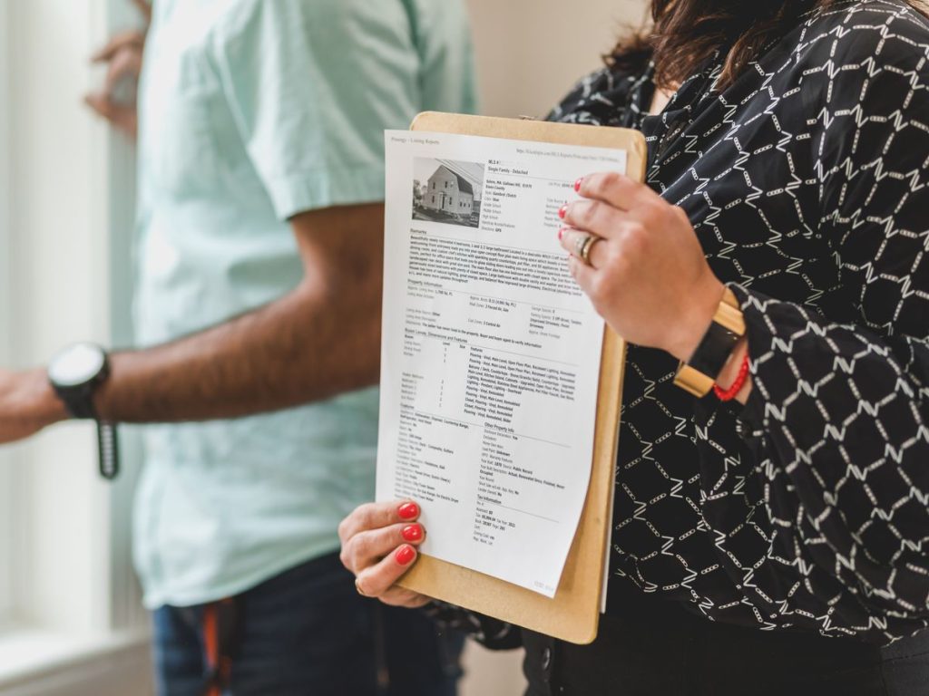 Real estate agent holding property documents on a clipboard in an office setting