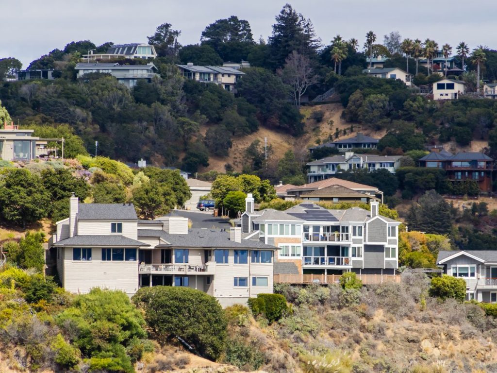 A picturesque view of modern houses on a hillside surrounded by lush greenery, showcasing urban residential architecture