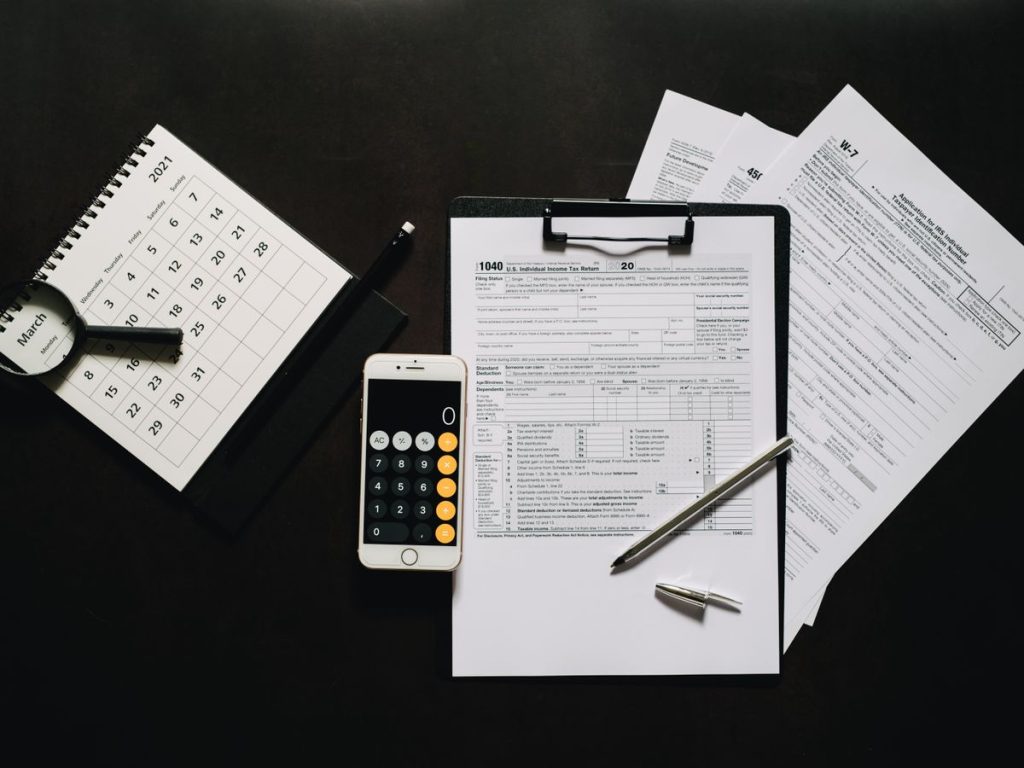 Flat lay of financial tools for tax preparation including forms, calculator, and calendar