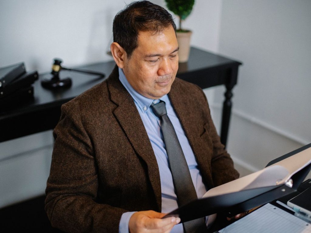 Professional in a suit reviewing a report in a folder at his desk