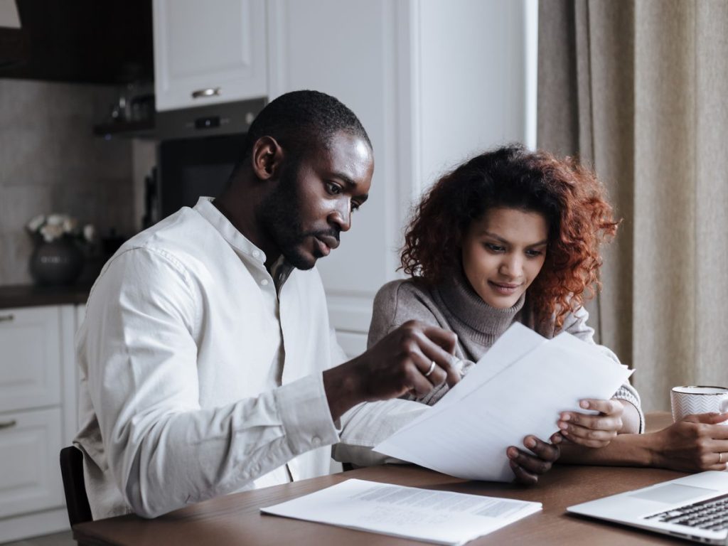 Couple working together on documents at home interior using a laptop