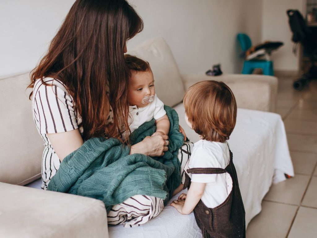 Mother and children share a warm moment on the sofa, filled with love and togetherness