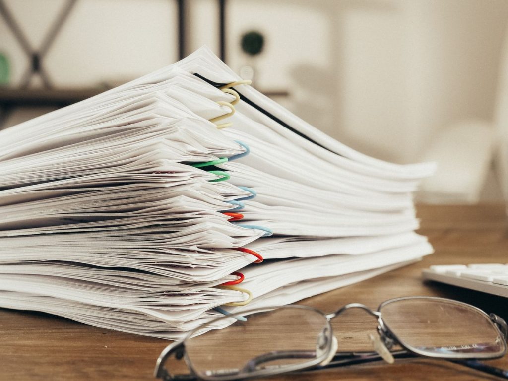 Close-up of a stack of office papers on a desk with glasses, emphasizing organization