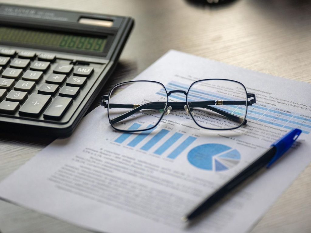 Financial document with a calculator, pen, and glasses symbolizing data analysis