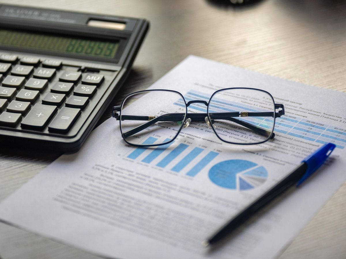 Financial document with a calculator, pen, and glasses symbolizing data analysis