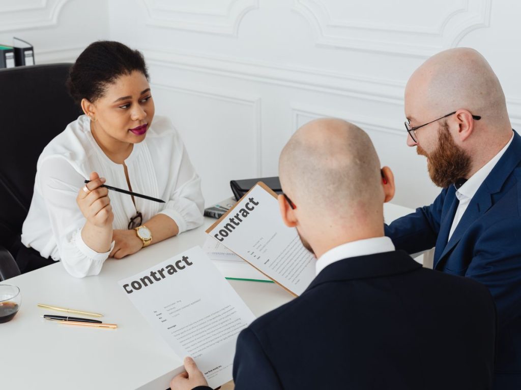 Three business professionals in discussion over a contract in a modern office setting
