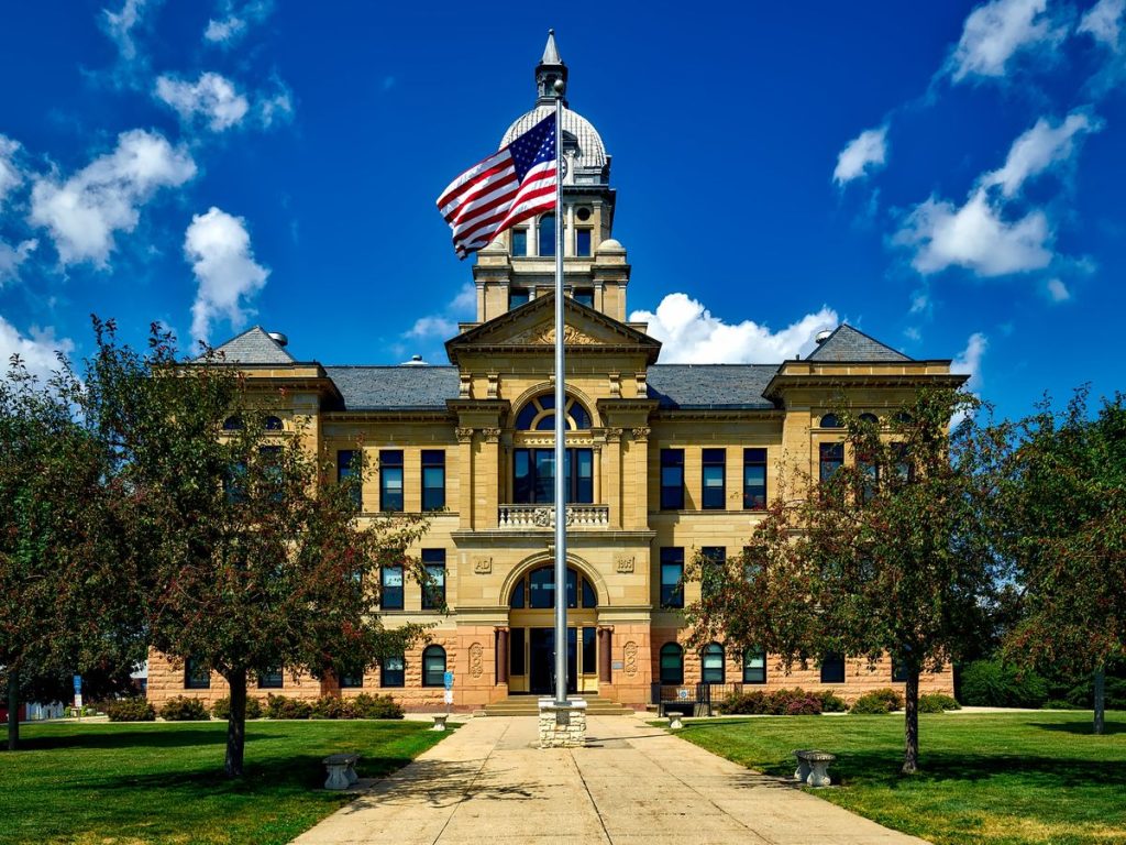 Grand courthouse with an American flag against a bright blue sky