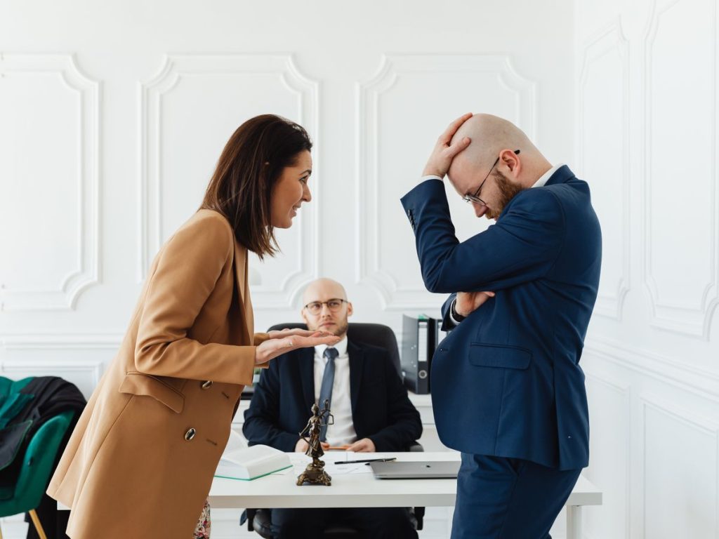 A couple having a heated argument in a law office with their attorney observing