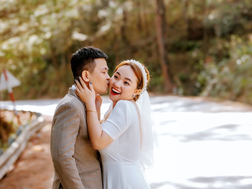 A joyful bride and groom smiling in a romantic embrace outdoors on a sunny day