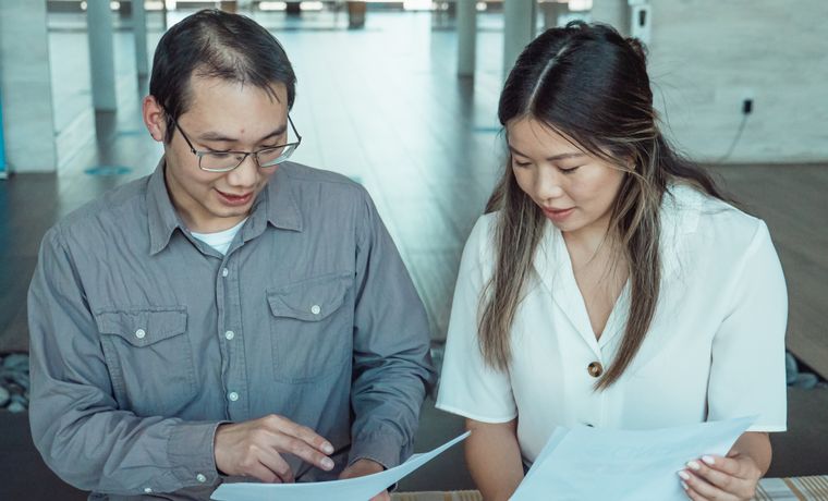 Two coworkers reviewing documents in a modern office, focused on teamwork and planning