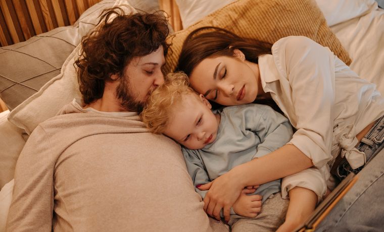 A loving family of three enjoying a relaxing moment in bed together, embracing warmth and affection